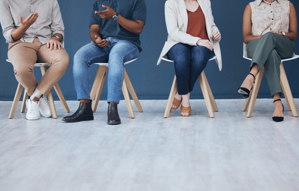 Interview, human resources and recruitment with business people sitting in line on chairs in a stud
